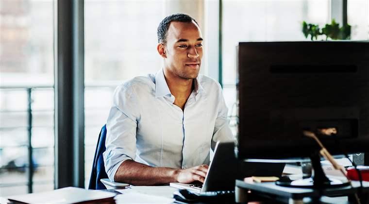 An office worker using working at his desk using a computer to review data.