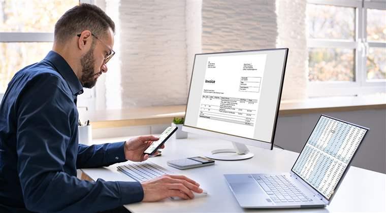 Young Man Looking At Online Taxes Invoice On Computer