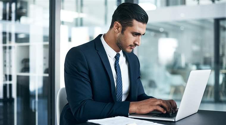 Shot of a young businessman working on a laptop in an office