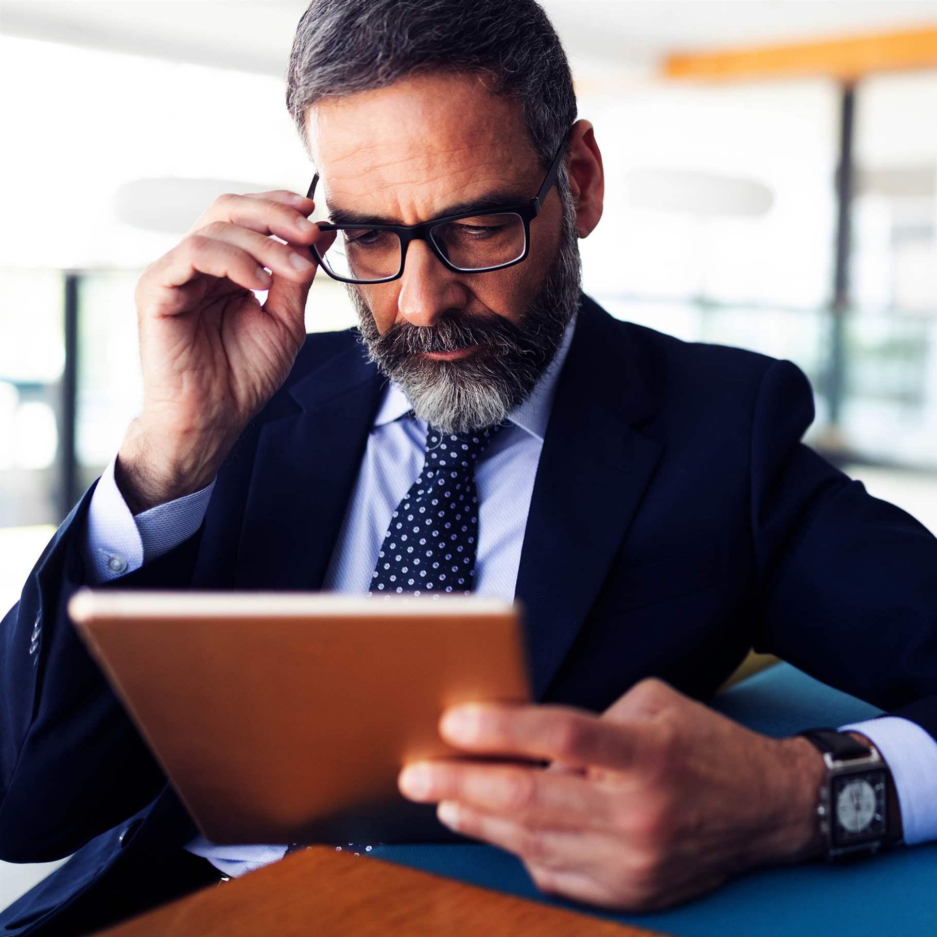 Serious man managing director of prosperous company is holding touch pad