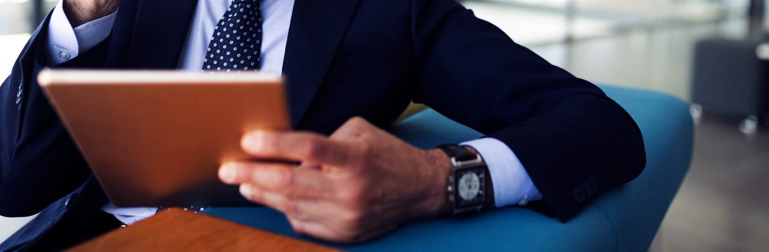 Serious man managing director of prosperous company is holding touch pad