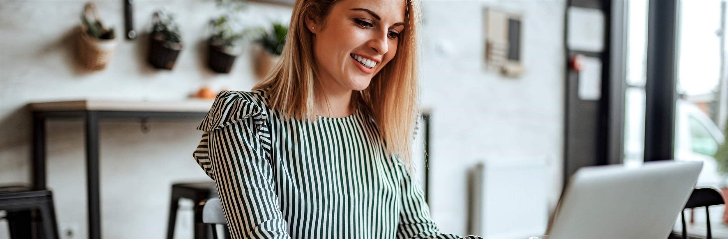 Smiling woman typing on laptop indoors.