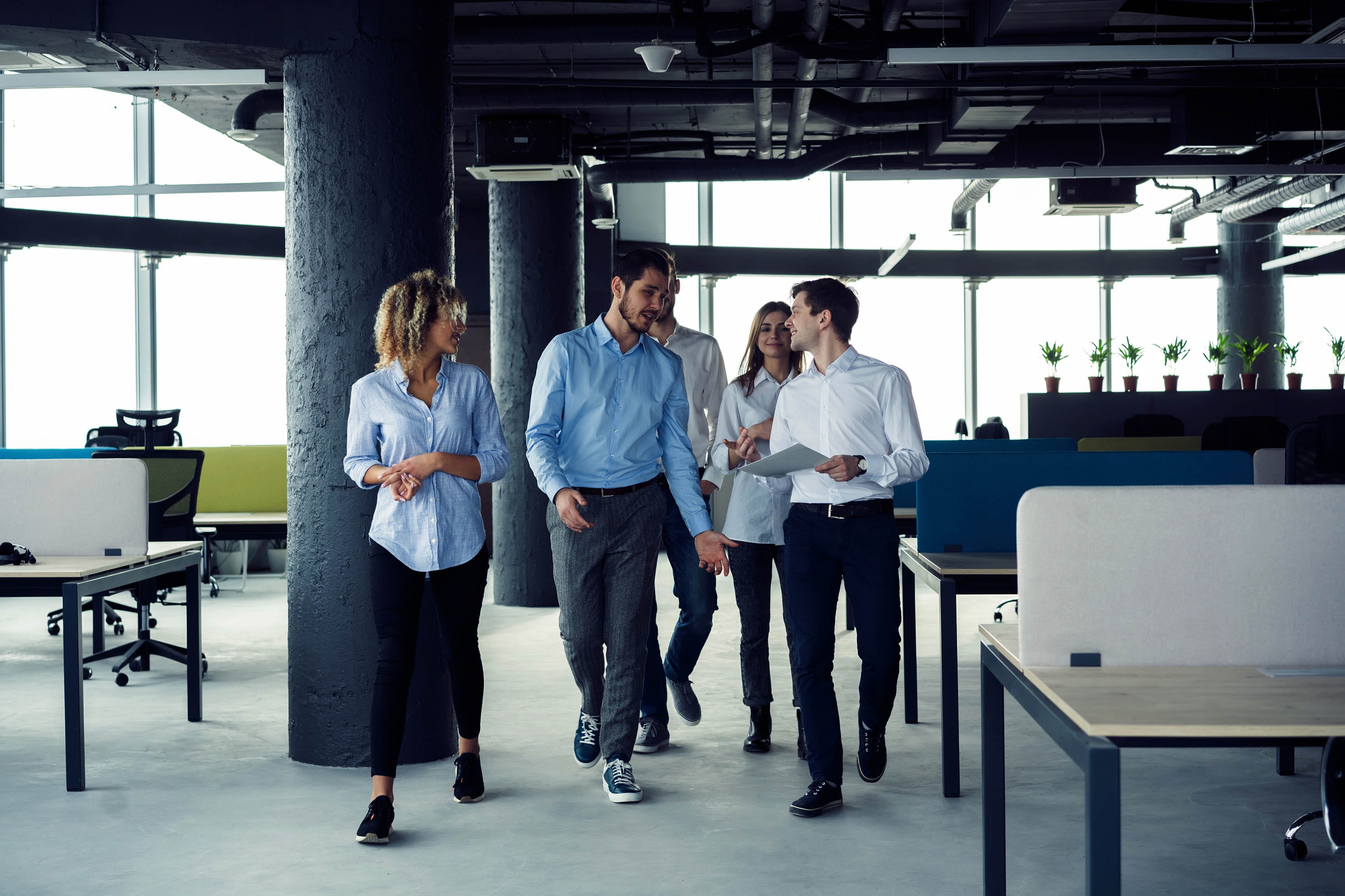 Taking their business on the move. Full length of young modern people in smart casual wear having a discussion while walking through the large modern office