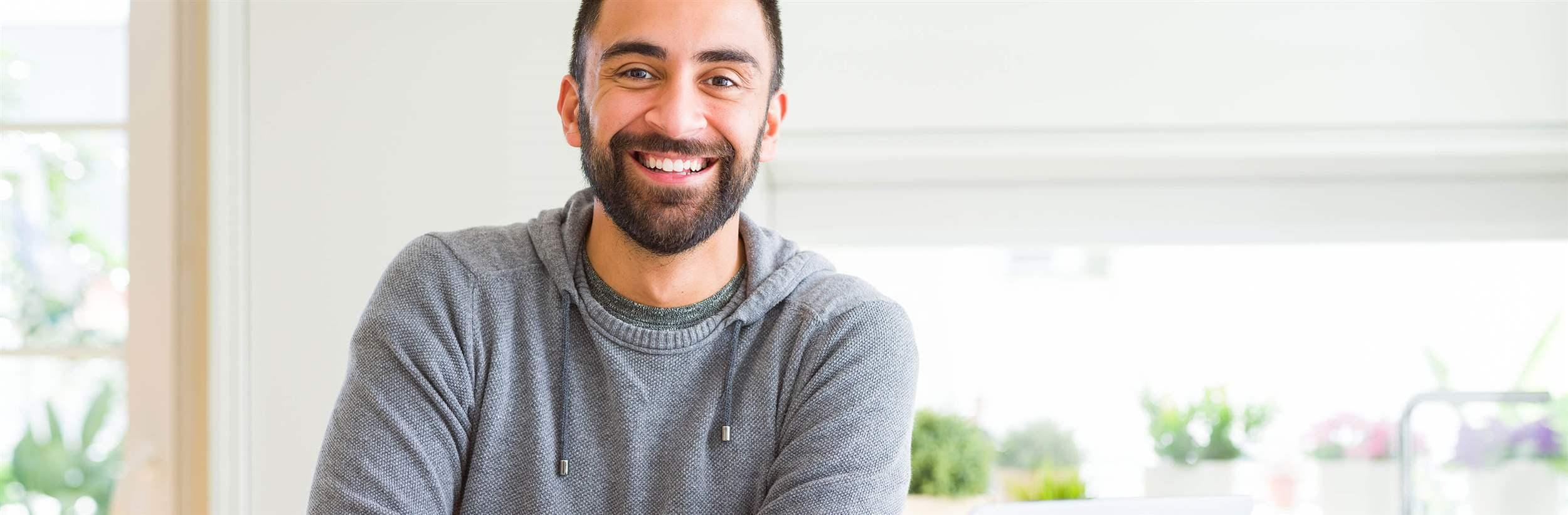 Handsome hispanic man working using computer laptop happy face smiling with crossed arms looking at the camera. Positive person.