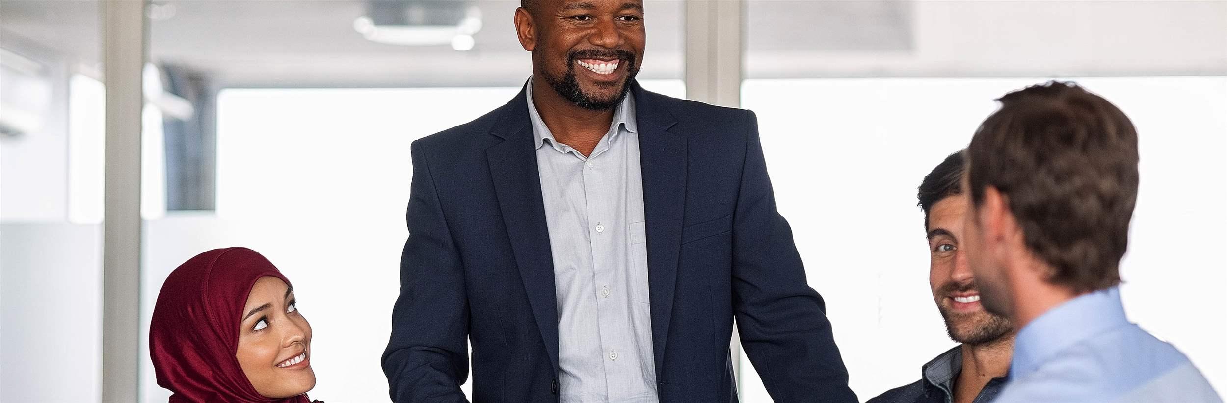 Entrepreneurs, partners and islamic woman conference in modern meeting room. Happy mature african businessman putting forward his suggestions to colleagues. Group of multiethnic business people brainstorming together. 