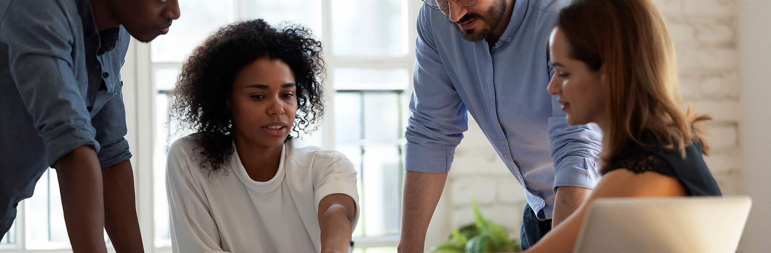 Motivated diverse employees team working together, sitting at table in boardroom, business partners discussing project documents, statistics or results, sharing startup ideas at meeting