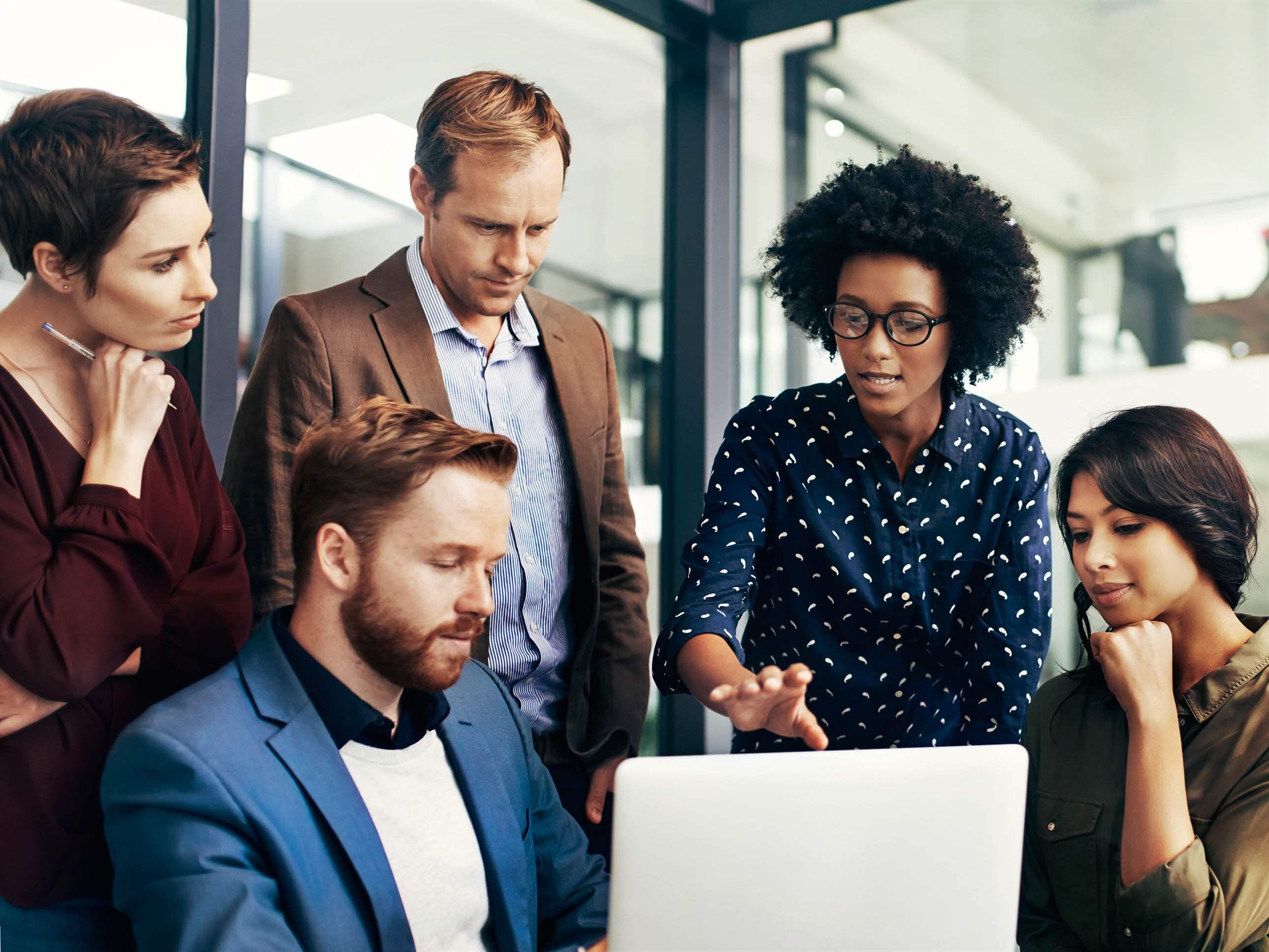 Shot of a group of colleagues using a laptop together at work
