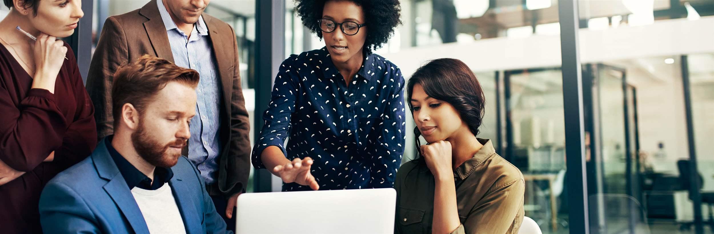 Shot of a group of colleagues using a laptop together at work