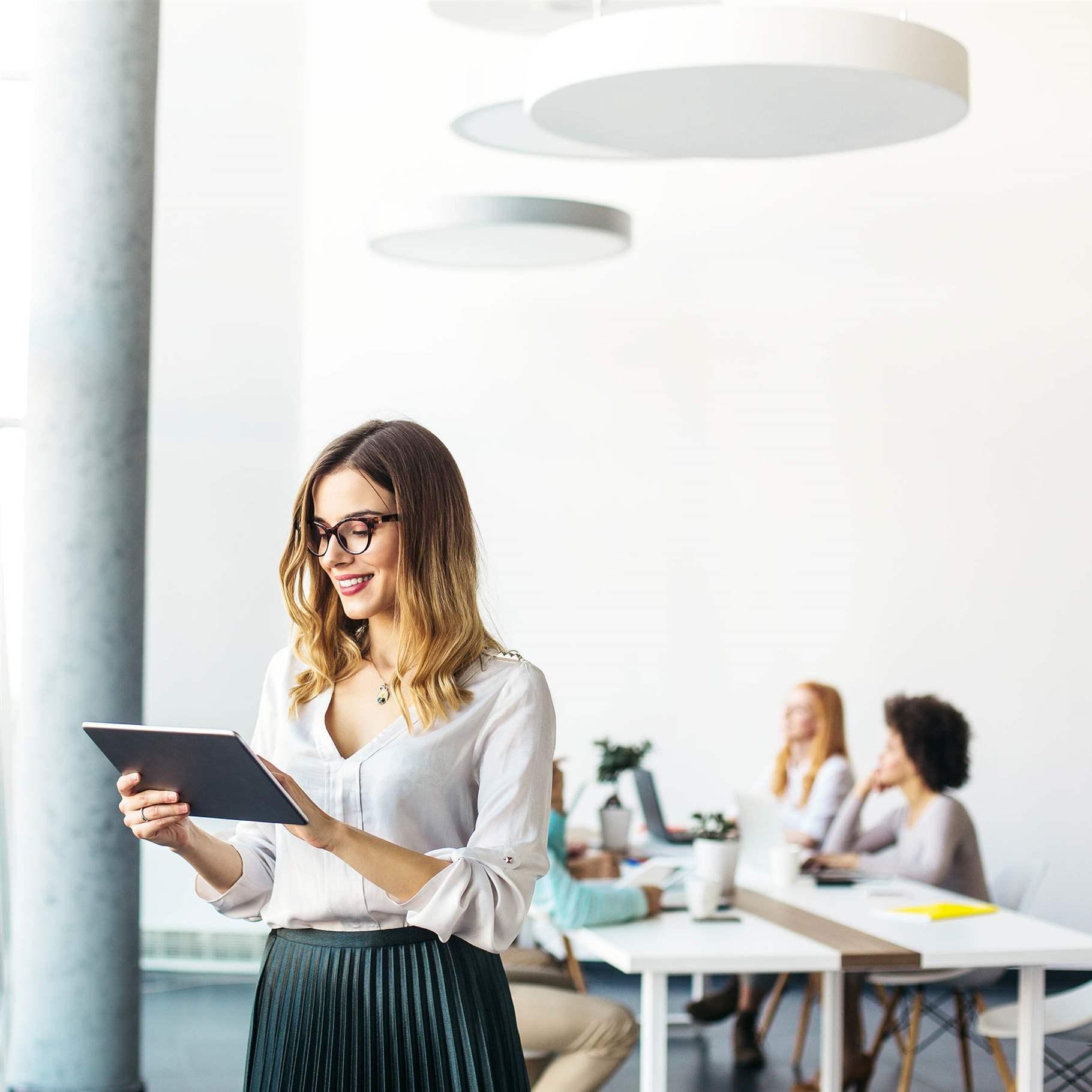 Beautiful businesswoman standing and working on a digital tablet computer in the modern office