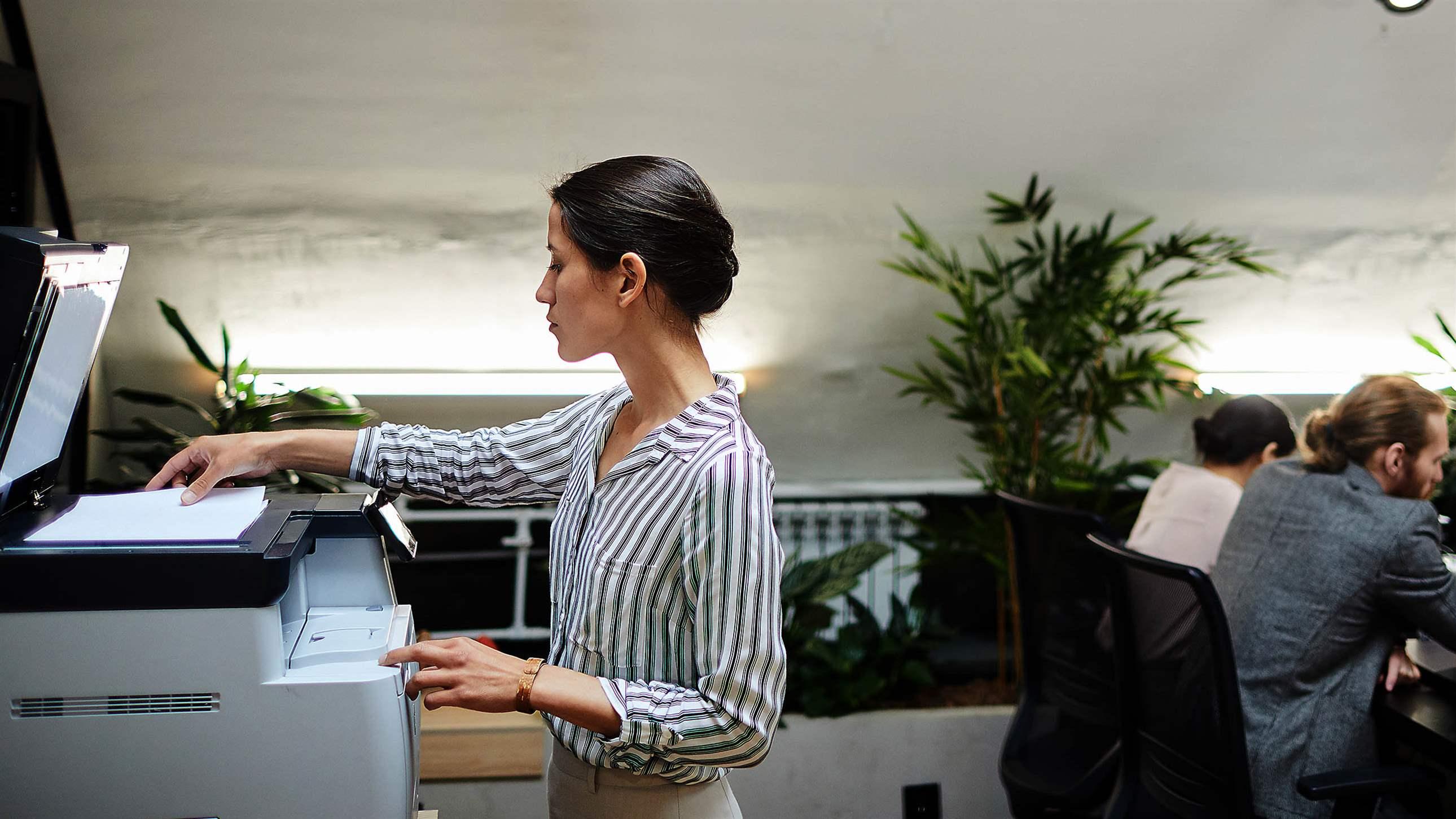 Side view portrait of young businesswoman scanning documents while working in office, copy space
