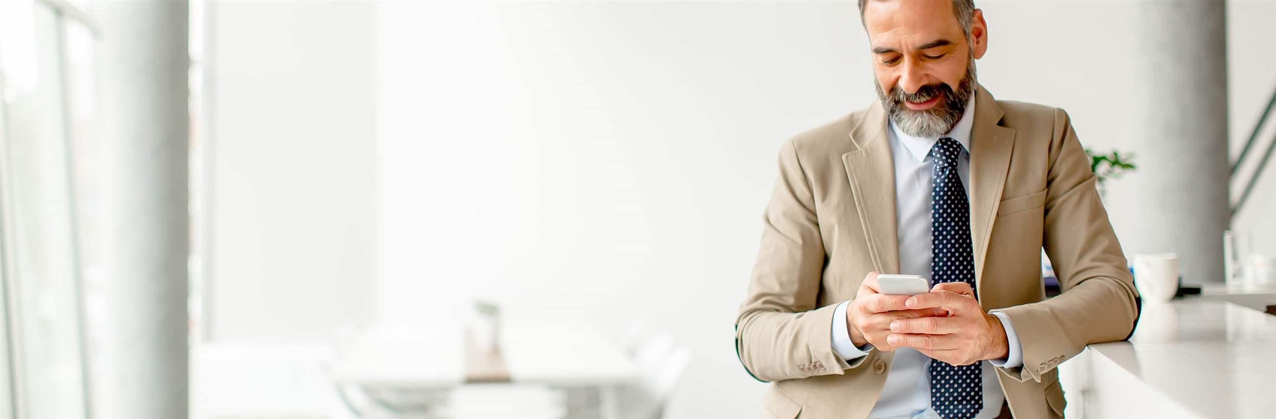 Handsome mature businessman with mobile phone in the office