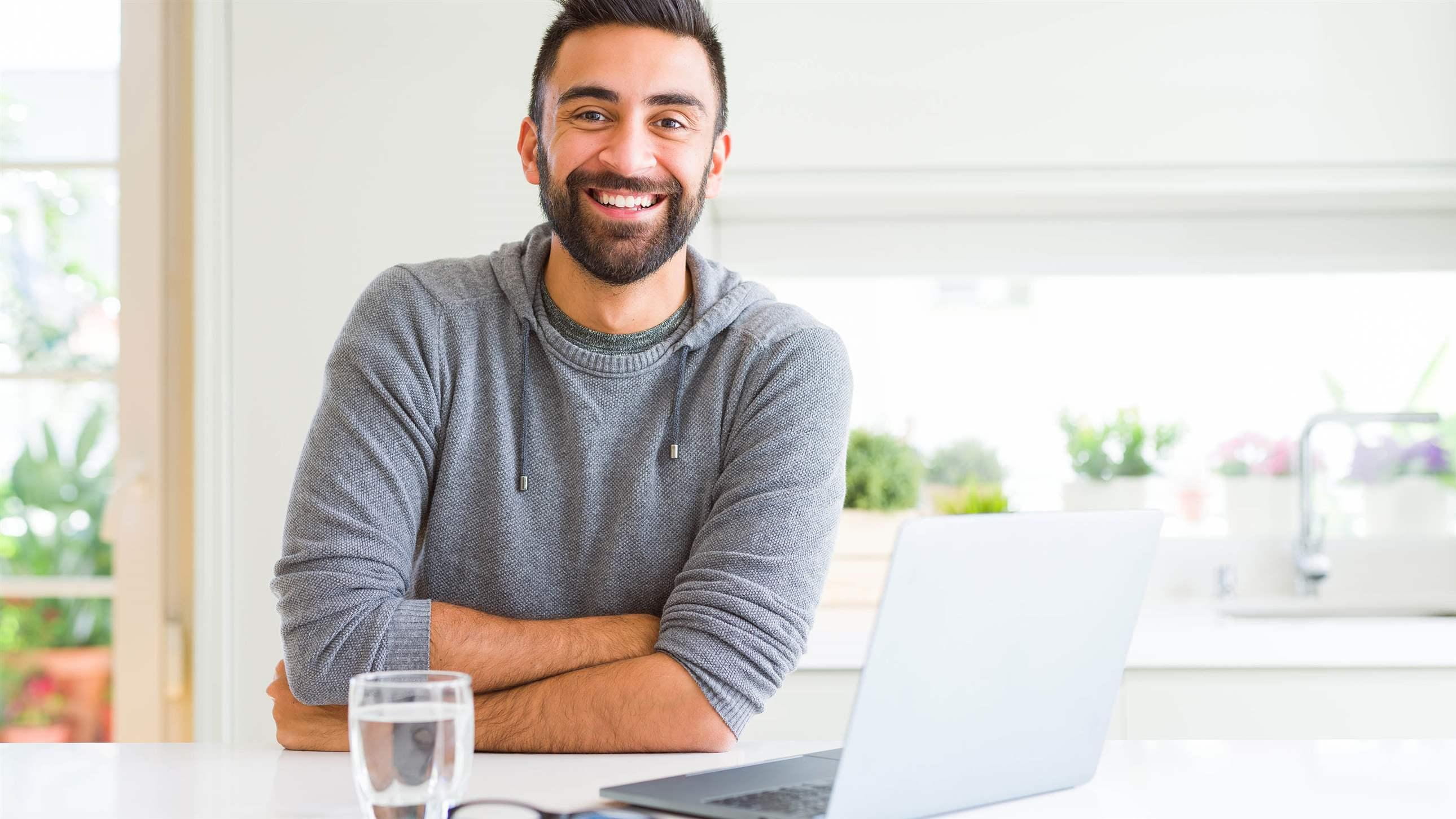 Handsome hispanic man working using computer laptop happy face smiling with crossed arms looking at the camera. Positive person.