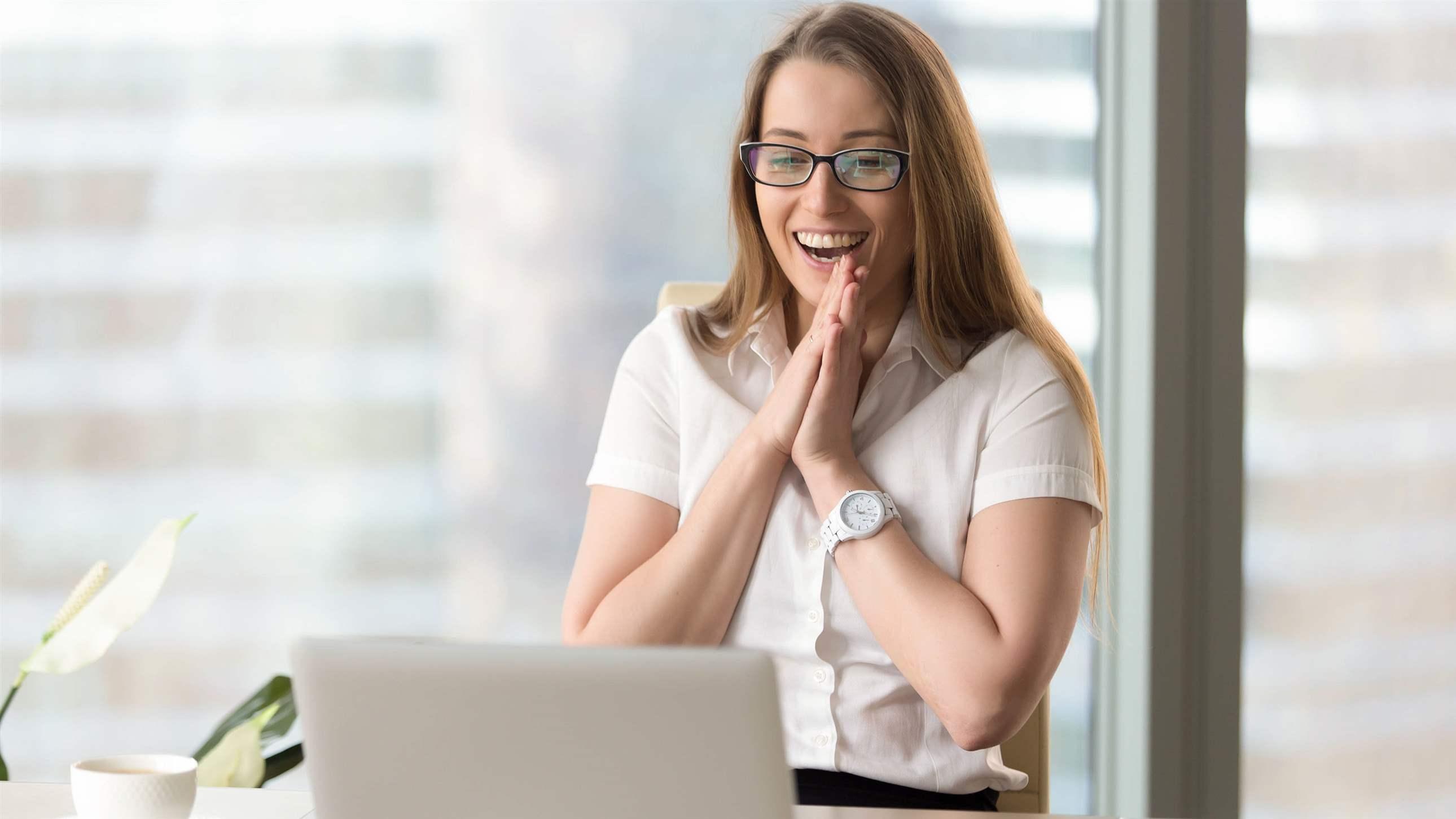 Happy businesswoman laughing with joy at workplace, gladly looking at laptop screen, feeling excited about online win, watching funny video on computer, enjoying positive good news in internet